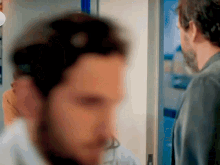 a blurry picture of two men standing next to each other .