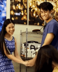 a man and a woman are holding hands in a room with a shelf in the background .