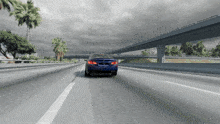a blue car is driving down a highway with a palm tree in the background