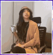 a woman in a hat is sitting in a chair holding a cup of coffee .