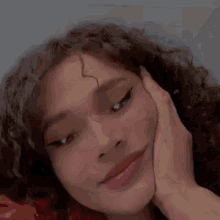 a close up of a woman with curly hair smiling and waving .
