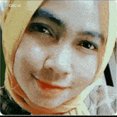 a woman wearing a hijab and a plaid shirt is smiling for the camera .