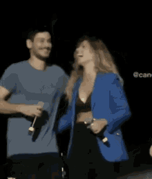 a woman in a blue jacket is hugging a man holding a microphone