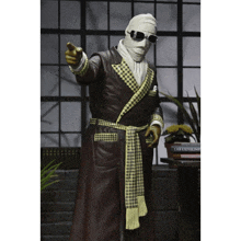 a statue of a man wearing a robe and goggles points his finger