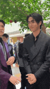 a man in a black suit is standing next to a woman in a purple shirt .