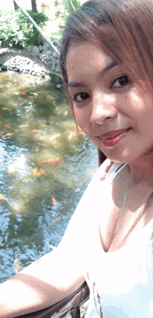 a woman taking a selfie in front of a pond with fish
