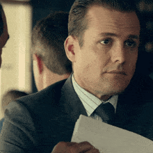 a man in a suit and tie is holding a piece of paper in his hand