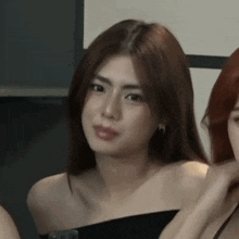 a close up of a woman wearing a black off the shoulder top and earrings .