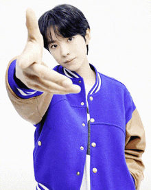 a man wearing a blue jacket with brown sleeves is making a hand gesture
