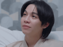 a young man is laying on a bed with his eyes closed and looking up .