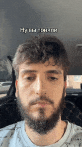 a man with a beard is sitting in the back seat of a car with a caption in russian