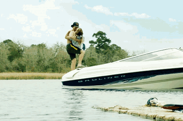 a man is carrying a woman on his shoulders while standing on a boat that says bruliner on the side of it