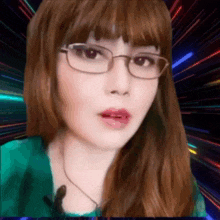 a woman wearing glasses and a green shirt is looking at the camera