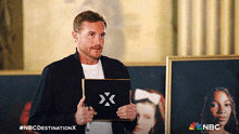 a man is holding a sign that says nbc destination x