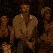a man and two women are sitting next to each other in a room .