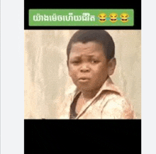 a young boy is making a funny face in front of a wall with smiley faces .