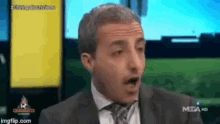 a man in a suit and tie is making a funny face on a tv show .