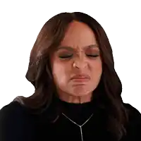 a woman wearing a black top and a necklace makes a funny face