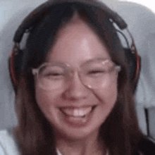 a woman wearing headphones and glasses is smiling and making a funny face .