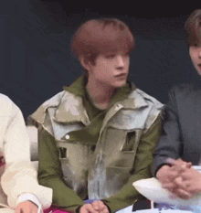 a group of people are sitting at a table and one of them is wearing a vest
