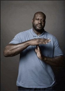 a man wearing a blue shirt is making a stop sign
