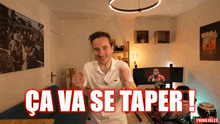a man standing in a room with the words ca va se taper written in red