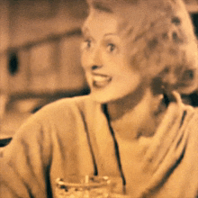 a woman is smiling and holding a glass