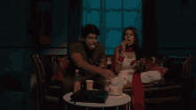 a man and a woman are sitting on a couch and the woman is looking at the camera .