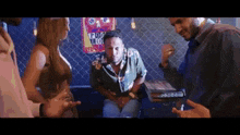 a group of people are standing around a table talking to each other in a bar .