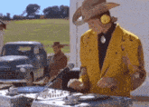 a man in a yellow jacket and cowboy hat is playing music on a turntable