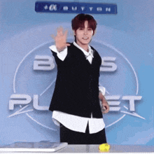 a young man stands in front of a sign that says button on it