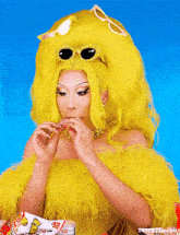 a woman wearing a yellow wig and sunglasses is eating a bag of chips