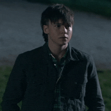 a young man in a black jacket and plaid shirt