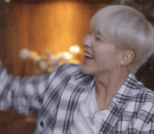 a man with short white hair is wearing a plaid shirt and earrings .