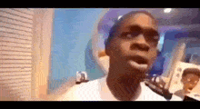 a man in a white shirt is standing in a room with a blue wall .