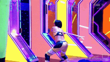 a female wrestler is holding a sword in front of a colorful wall .
