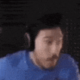 a man wearing headphones and a blue shirt has a surprised look on his face