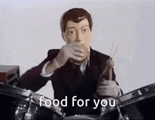 a man in a suit is playing drums and drinking from a straw .