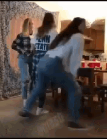 a group of young women are dancing in a room . one of the girls is wearing a shirt that says pain state .