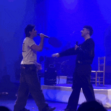 a man singing into a microphone while another man looks on