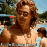 a shirtless man wearing sunglasses and a necklace is standing next to a pool .