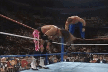 two wrestlers are wrestling in a ring with a wrestler 's logo on the ring