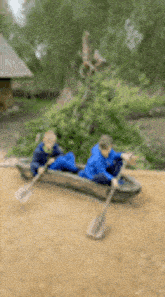 two young boys are rowing a canoe on a river .