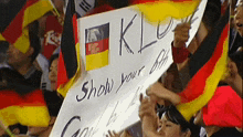 a crowd of people holding flags and a sign that says " show your off "
