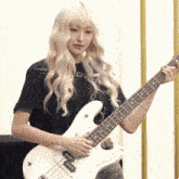a girl with blonde hair is holding a white guitar