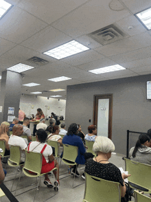 a group of people sitting in a waiting room with a sign on the wall that says ' a ' on it