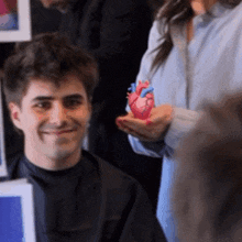 a man is holding a model of a human heart