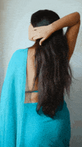 a woman in a blue saree holds her hair in her hand