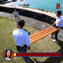 a man is carrying a large wooden plank with the letter n on the bottom right