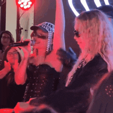 a woman singing into a microphone while wearing a hat that says chanel on it